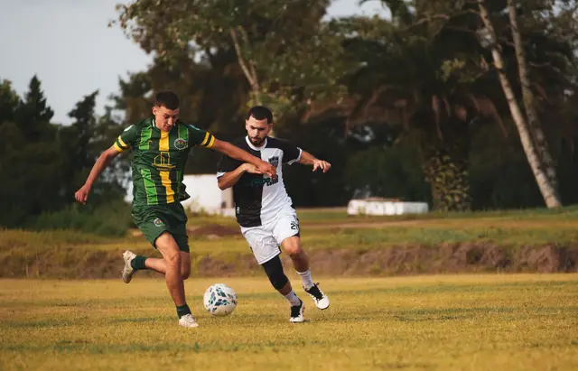 Dos jugadores en disputa hombro a hombro bajo luz dorada