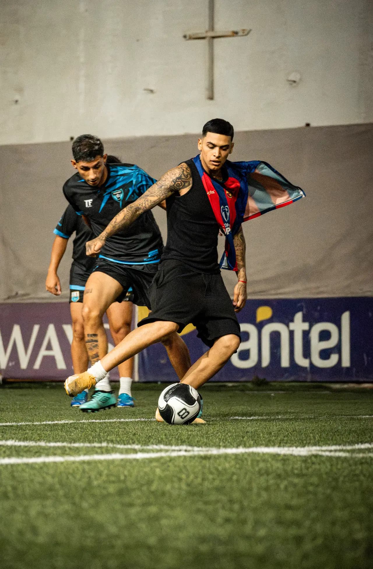 Jugador con la pelota protegiendo ante un rival de camiseta celeste y negra