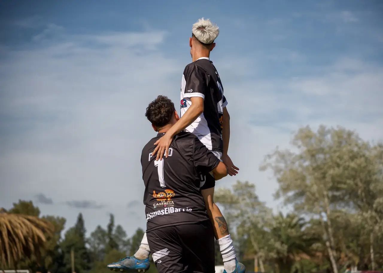 Jugador número 7 abrazando y levantando a un compañero en un festejo de gol