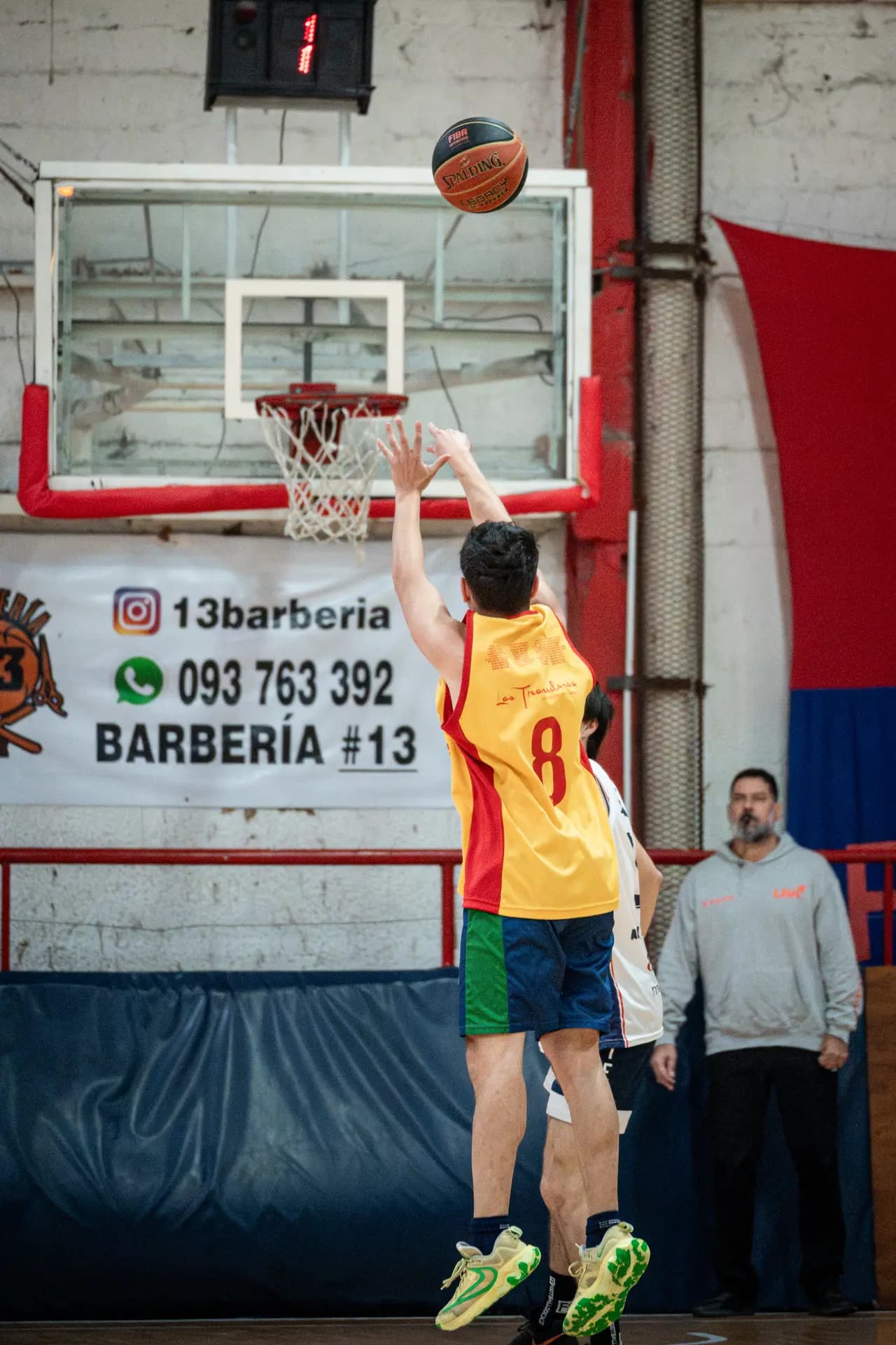 Jugador número 8 lanzando al aro ante la defensa rival