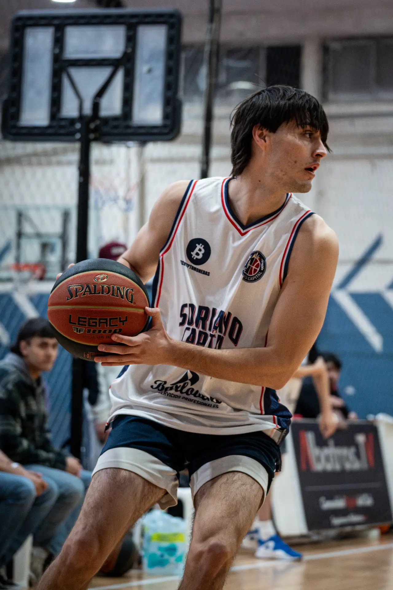 Jugador de camiseta blanca controlando la pelota durante un partido de básquetbol