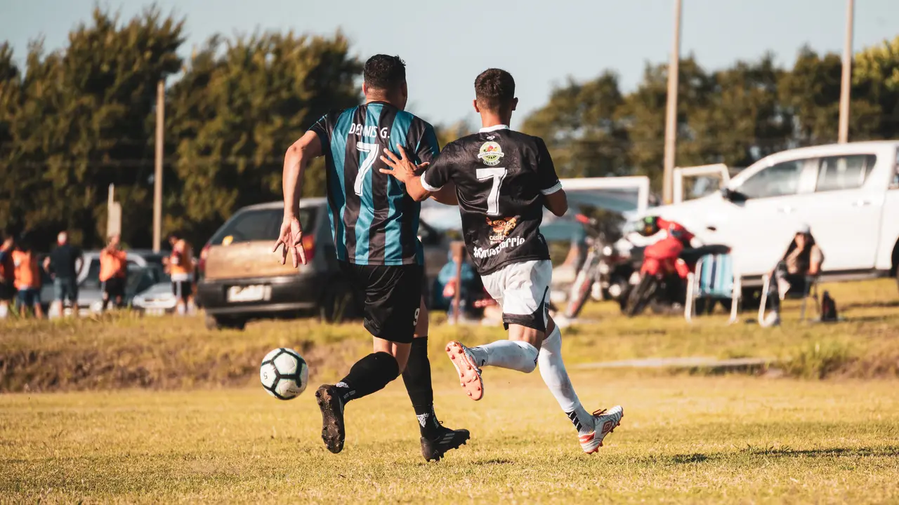 Dos jugadores corriendo codo a codo persiguiendo la pelota