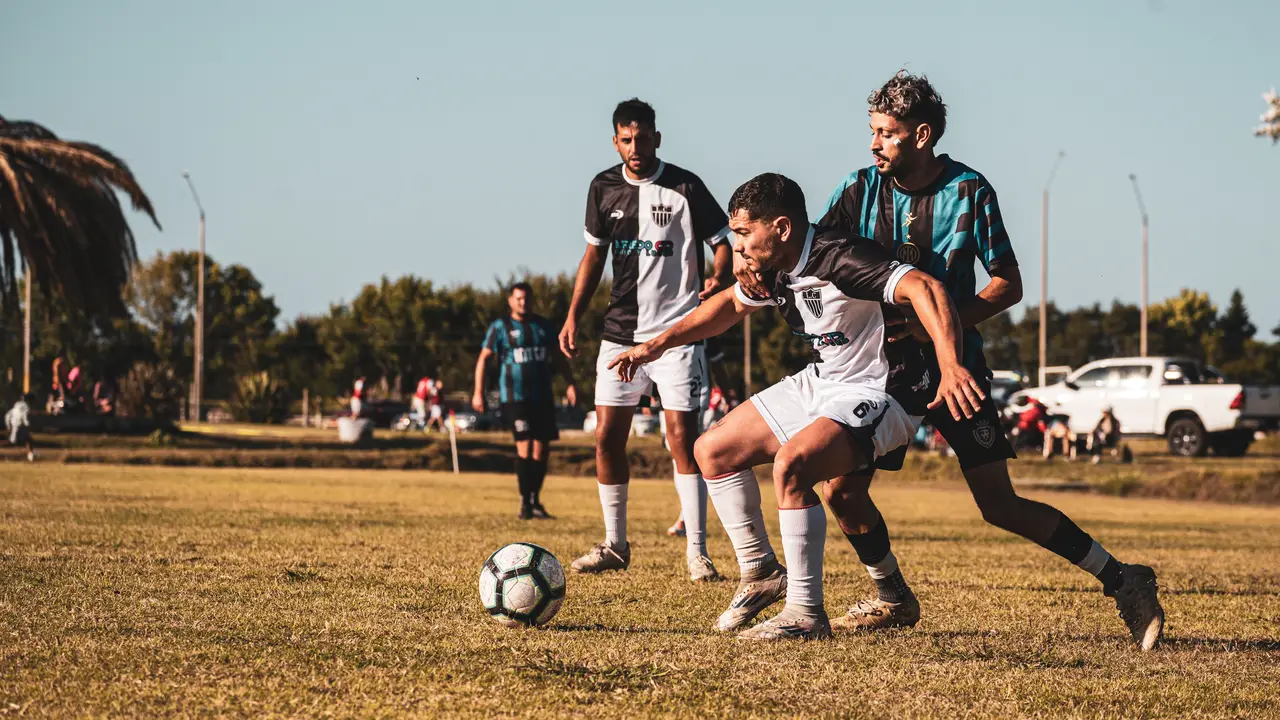 Jugador driblando ante un rival con compañeros observando